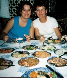 Two women sitting at the end of a table laden with plates of food.