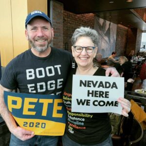 A man and a woman, wearing Pete Buttigieg gear, holding signs. One says Pete 2020; the other says, Nevada here we come.