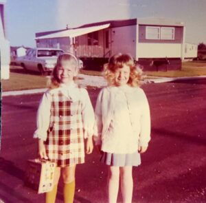 two young children standing in front of a a mobile home